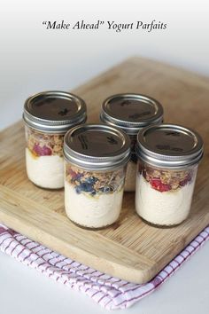 four jars filled with food sitting on top of a wooden tray