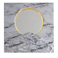 a round mirror sitting on top of a white and gold marble wall mounted shelf next to a mountain