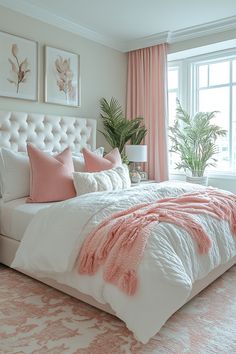 a white bed with pink pillows and blankets in a bedroom next to a large window