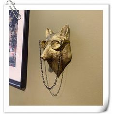 a cat mask hanging on the wall next to a framed photo and chain link necklace