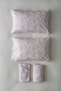 the pillows and pillow cases are all made up in different shades of purple, white and grey