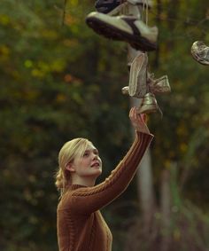 a woman holding up some shoes in the air