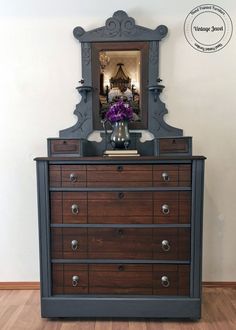 a dresser with a mirror on top of it next to a vase filled with flowers