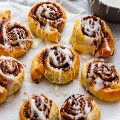 cinnamon rolls with icing sitting on top of white paper