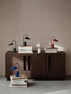 a sideboard with two lamps, books and a lamp on it next to each other