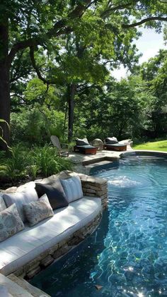 an outdoor swimming pool with couches and trees in the back ground, surrounded by lush greenery