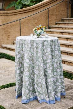 a table with flowers on it in front of some stairs and steps leading up to the upper level