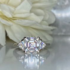 three stone diamond ring sitting on top of a white flower