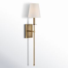 a wall light with a white shade on the side and a gold pole attached to it