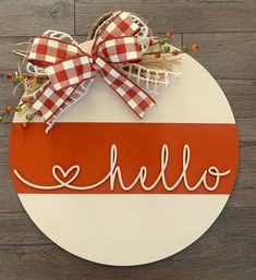 a red and white sign that says hello with a bow hanging on the front of it