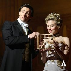 a man in a tuxedo holding a bird cage next to a woman in a white dress