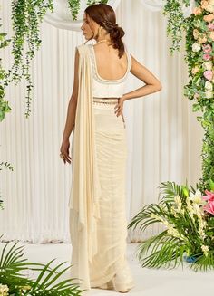 Featuring an ivory-hued shimmer georgette pre-draped saree paired with a U-neckline bustier detailed with pearl, bead, and sequin work. The look is finished with an embellished long cape featuring pearl tassels and a belt. This ensemble is a ready to wear saree for your ease ! Composition : Saree: Georgette, Blouse: Silk, Cape & Belt: Crepe Care: Dry Clean Only and Vacuum Storage All products can be customised for sleeves, length of blouse and neck design Delivery : 4-6 weeks as the product is h Embellished Pre-draped Saree For Wedding, Fitted Pre-draped Saree With Sequins, Elegant Draped Blouse With Sequins, Elegant Draped Sequin Lehenga, Sequin Pre-draped Fitted Saree, Reception Pre-draped Saree With Pearl Embroidery, Elegant Pre-draped Saree With Pearl Embroidery For Evening, Elegant Draped Sequin Blouse, Fitted Saree With Pearl Embroidery For Reception