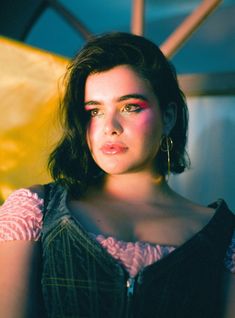 a woman with dark hair and pink makeup looks at the camera