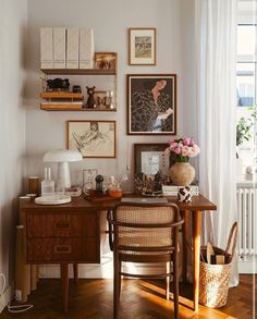 a desk with some pictures on the wall above it and a chair next to it