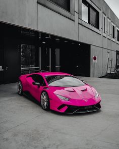 a pink sports car parked in front of a building