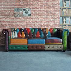 a multicolored couch sitting in front of a brick wall with bookshelves