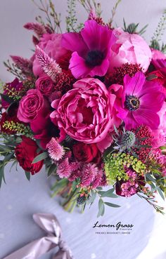 a bouquet of pink and red flowers sitting on top of a white tablecloth covered table