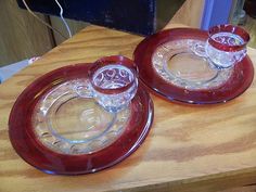 two red glass dishes sitting on top of a wooden table