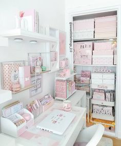 a white desk topped with lots of pink and white items next to a shelf filled with boxes