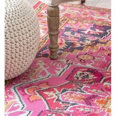 a pink rug with an ornate design on the floor and foot stool in front of it