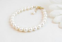 "A classic real freshwater pearl bracelet for newborn, infant, baby, child, little girl, tween or teen. This keepsake bracelet is created with Grade-A 5.5mm round freshwater pearls and a 14K gold-filled oval lobster clasp with a 1/2\" \"Grow with Me\" extender chain. Arrives packaged in my signature high-quality reusable canvas gift bag. Beautiful and ready for gift giving. S I Z I N G . G U I D E The bracelet should be 3/4\" larger than her snug wrist measurement. If you are unable to measure, Classic White Bracelets For Mother's Day, Elegant Pearl Jewelry For Baptism, Classic White Pearl Bracelet For Mother's Day, Elegant Adjustable Pearl Bracelet For Baptism, Elegant Pearl White Jewelry For Baptism, Classic Adjustable Jewelry For First Communion, Elegant Pearl Bracelet For First Communion, Elegant Pearl White Jewelry For First Communion, Elegant White Bracelets