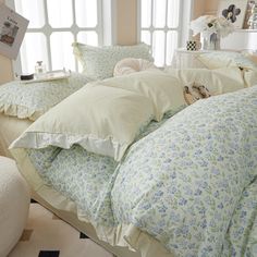 a bed covered in lots of pillows next to a window