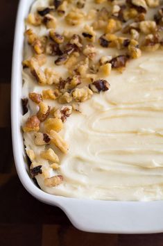 a white casserole dish with carrots and nuts on top, ready to be eaten