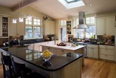 a large kitchen with an island and skylight in the center, surrounded by wood flooring