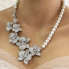 Elevate your bridal look with our Bridal Statement Earrings Necklace Set. Crafted with stunning crystal pearls and intricate orchid flowers, this unique wedding jewelry set adds a touch of elegance to your special day. Designed as the perfect gift for brides, each piece reflects meticulous attention to detail and timeless beauty. Let our set be a cherished part of your unforgettable moments. Embrace authenticity and sparkle with this exquisite ensemble. Dazzle on your special day with our exquis White Flower Bridal Necklace For Wedding, White Floral Bridal Necklace For Wedding, White Crystal Embellished Bridal Earrings For Wedding, Silver Flower Bridal Necklace For Wedding, White Crystal Embellished Bridal Necklace, White Crystal Embellished Bridal Necklace For Wedding, Pearl White Crystal Bridal Necklace For Wedding, Flower Shaped Pearl Necklace For Weddings, Flower Crystal Wedding Necklace