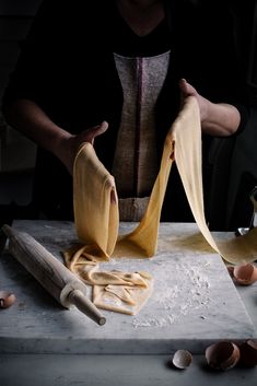 a woman is making pasta with her hands and two pieces of bread on the table