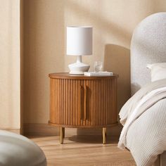 a nightstand with a lamp on top of it next to a bed in a room