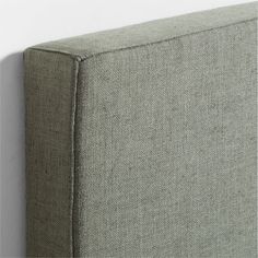 a close up view of the corner of a gray fabric bed headboard and foot board