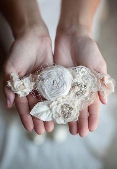 a woman's hands holding a white flower and lace object in her left hand