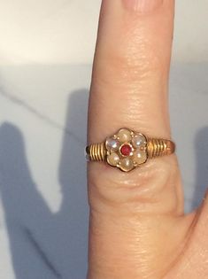 a woman's finger with a ring on it and a red stone in the middle