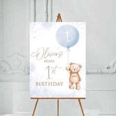 an easel with a teddy bear holding a blue balloon on it's side