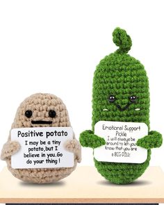 two crocheted stuffed toys sitting on top of a table holding signs that read positive potato and i may be a tiny potato