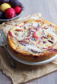 a cake sitting on top of a white plate next to a bowl full of fruit