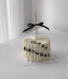 a birthday cake with the words happy birthday written on it and a black ribbon tied to top