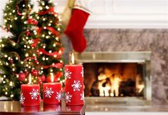 three red candles with white snowflakes on them in front of a christmas tree