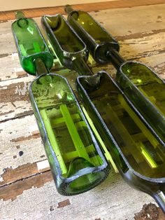 three green glass bottles sitting on top of a wooden table