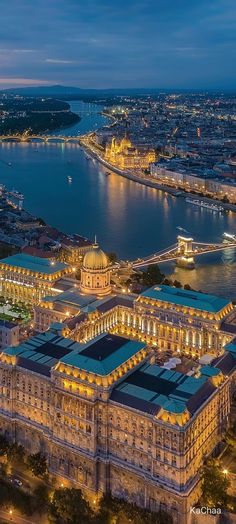 an aerial view of a city at night with lots of lights on the buildings and water in the background