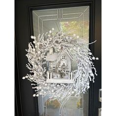 a wreath made out of fake branches on a front door with a house in the background