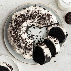 a chocolate cake with white frosting and oreo cookies on the side next to it