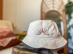 a white hat sitting on top of a piece of wood next to a chair and mirror