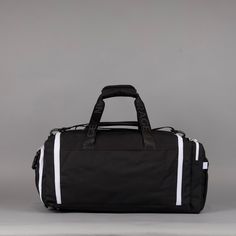 a black duffel bag sitting on top of a white and grey floor next to a gray wall