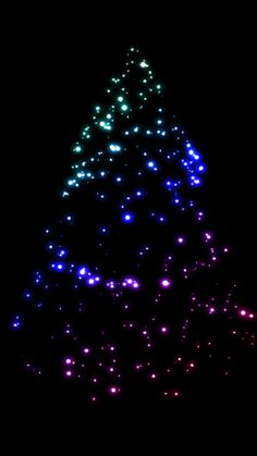 a large christmas tree is lit up in the dark with blue and green lights on it