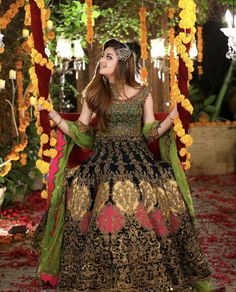 a woman in a black and gold dress standing under a canopy with flowers on it