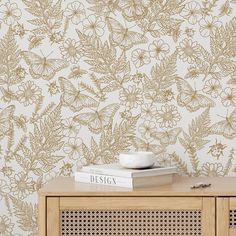 a wooden cabinet with books on top of it and a wallpaper design behind it