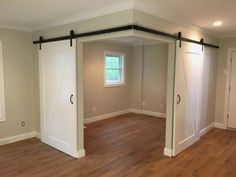 an empty room with sliding doors and hard wood floors