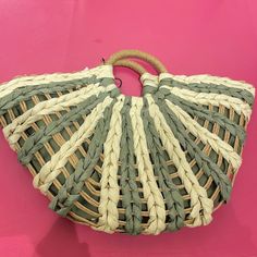 a green and white woven purse on a pink background